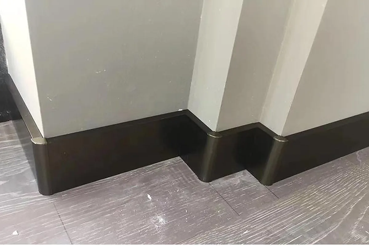 Dark stainless steel baseboards fitted around interior wall corners